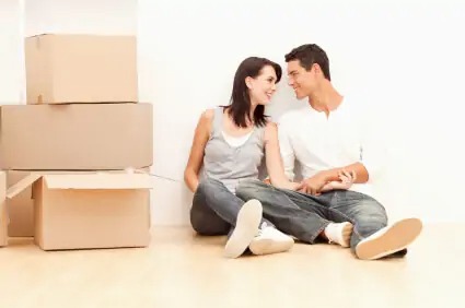 a couple sitting on the floor by moving boxes